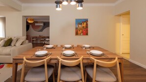 A dining area with a wooden table set for four, surrounded by chairs, with a painting on the wall and a ceiling light fixture above. - Kennah Lourina | Near Citystars, Heliopolis (Cairo)