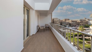 A balcony with a view of a cityscape, a table, and two chairs. - Kennah Lourina | Near Citystars, Heliopolis (Cairo)