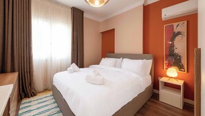 A neatly made bed with white linens and towels, a bedside lamp, and a painting on the wall. - Kennah Lourina | Near Citystars, Heliopolis (Cairo)