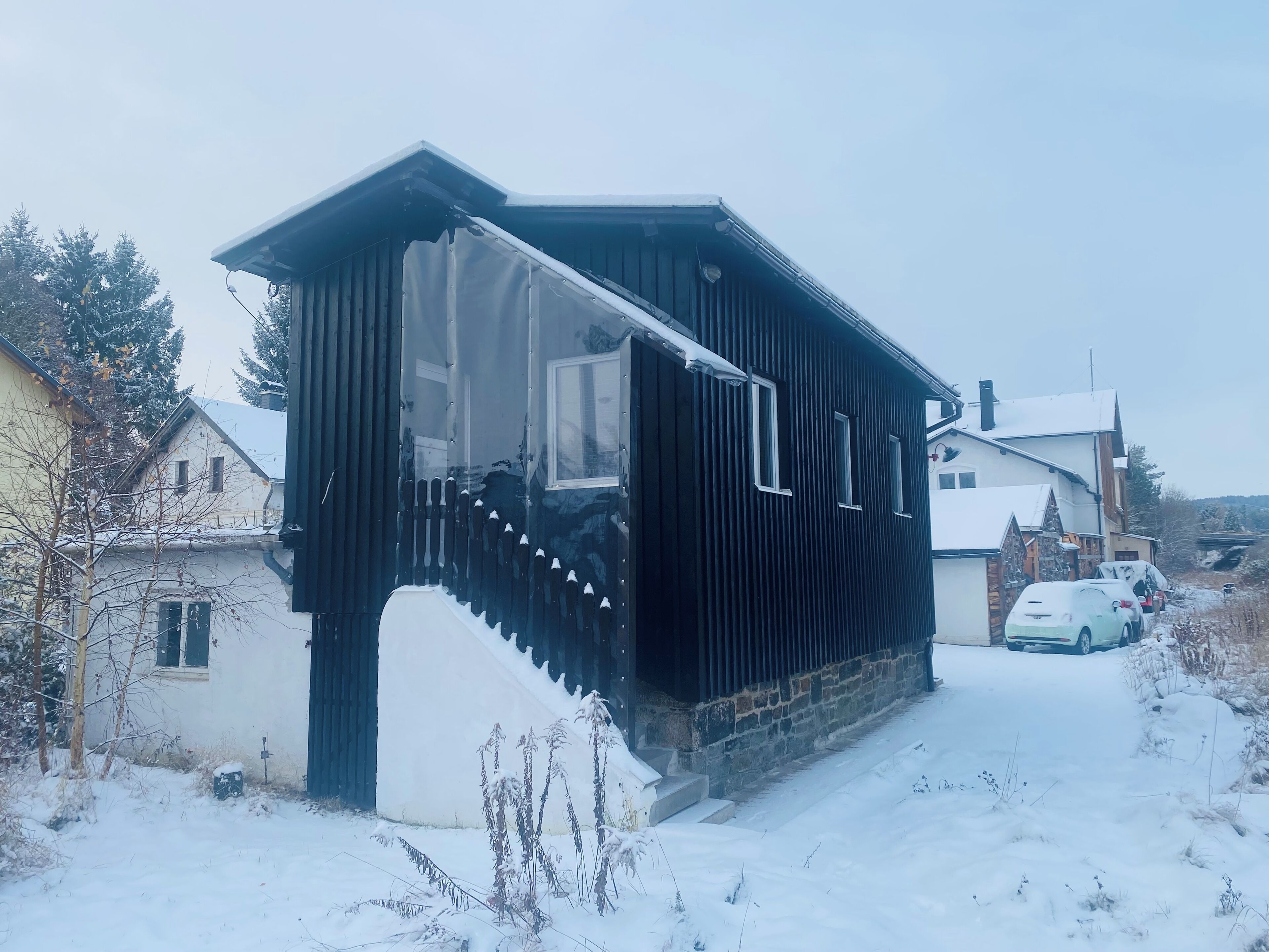 Un edificio moderno negro con techo inclinado y una escalera que lleva a una puerta.