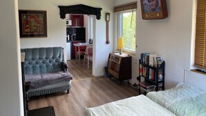 Una sala de estar acogedora con un sofá, una mesita, una estantería y una zona de cocina al fondo.