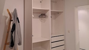 A walk-in closet with open shelves, a hanging rod, and a wooden ladder.