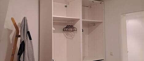 A walk-in closet with open shelves, a hanging rod, and a wooden ladder.