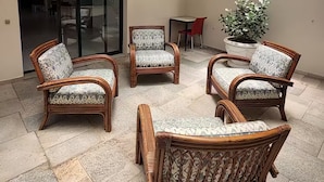 Un amplio patio con mobiliario de mimbre y una planta en maceta.