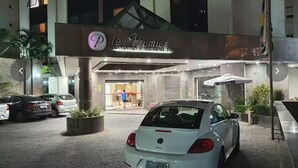 Un coche blanco estacionado frente a la entrada de un hotel con un letrero que dice "Le Premier".