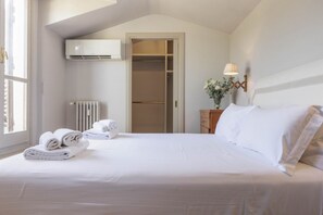 A bedroom with a bed, a radiator, a wardrobe, and a nightstand with a lamp.