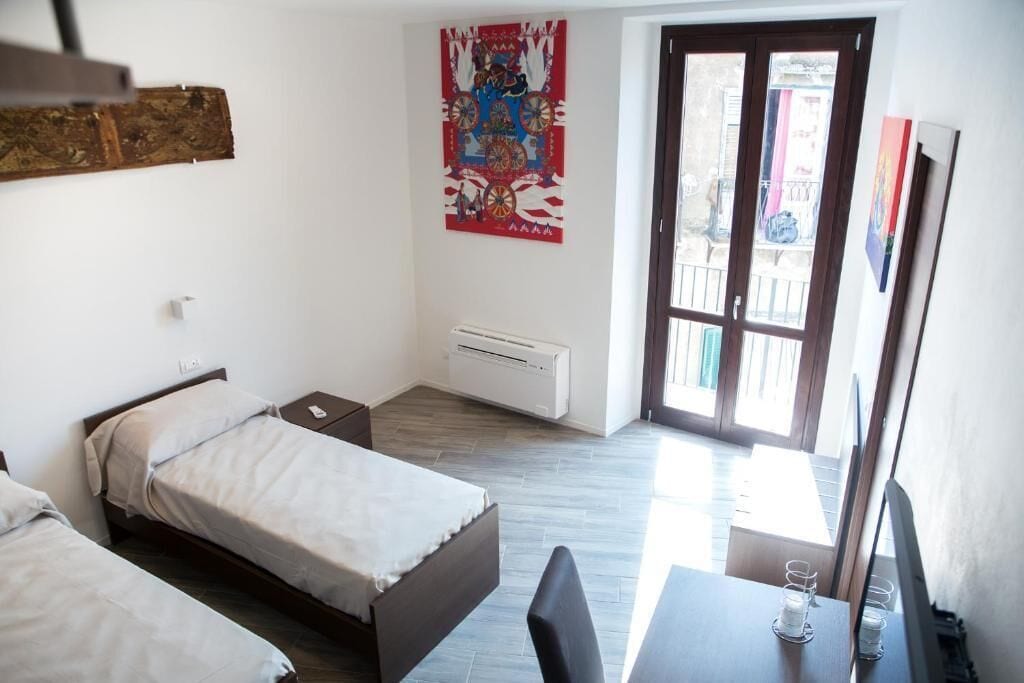 Una habitación pequeña y limpia con dos camas, un escritorio y una ventana.