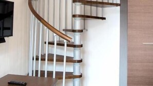 Un escalier en colimaçon avec des marches en bois et des rampes blanches, menant à l’étage supérieur.