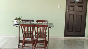 A reception area with a reception desk, two wooden chairs, a potted plant, a sign with a phone number, and a door. - POUSADA DECARLI (Florianopolis)