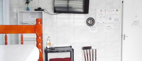 Una habitación de hotel con una cama, un televisor montado en la pared, un escritorio con una silla y una puerta con un cartel.