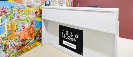 A reception desk with a colorful cityscape mural on the wall behind it.