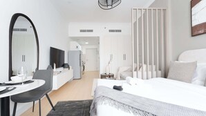 Moderni hotellihuone, jossa on sänky, työpöytä tuolilla, televisio ja suuri peili.