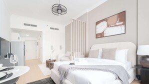 Moderni hotellihuone, jossa on suuri sänky, työpöytä tuolilla, ruokapöytä ja taulu seinällä.