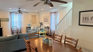 A dining area with a wooden table, chairs, and a ceiling fan. - Three Pines- Screen Porch - Close to Town - Newly Renovated (Chincoteague)