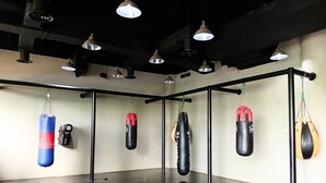 Une salle de sport équipée de sacs de frappe, d’une barre de traction et d’un éclairage supérieur.
