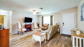 A living room with a sofa, chairs, a coffee table, a television, and a fireplace. - Explore Weeki Wachee Springs: Pet-friendly Home (Brooksville)