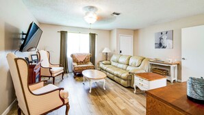 A living room with a sofa, chairs, a coffee table, a TV, and a lamp. - Explore Weeki Wachee Springs: Pet-friendly Home (Brooksville)