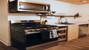 A modern kitchen with a stainless steel stove, oven, and microwave, wooden cabinets, and a wooden ceiling. - The Aviator: Serene Ambience & Stylish Comfort (Madison)