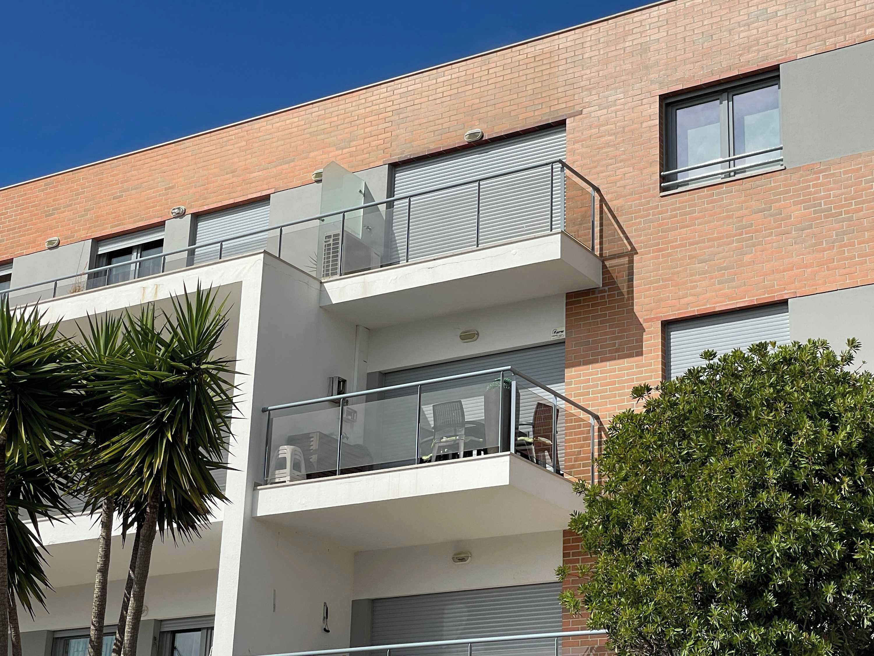 A modern multi-story building with balconies, large windows, and a brick facade.