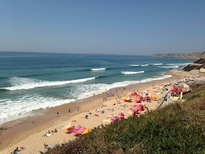 A beach with umbrellas and people.