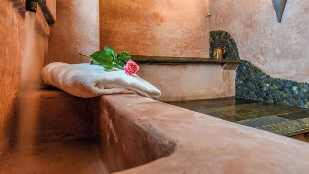 A stone bathtub with a towel and a rose. - Hôtel Spa Mendi Alde (Ossès)