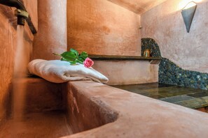 Una bañera de piedra con una toalla y una rosa.