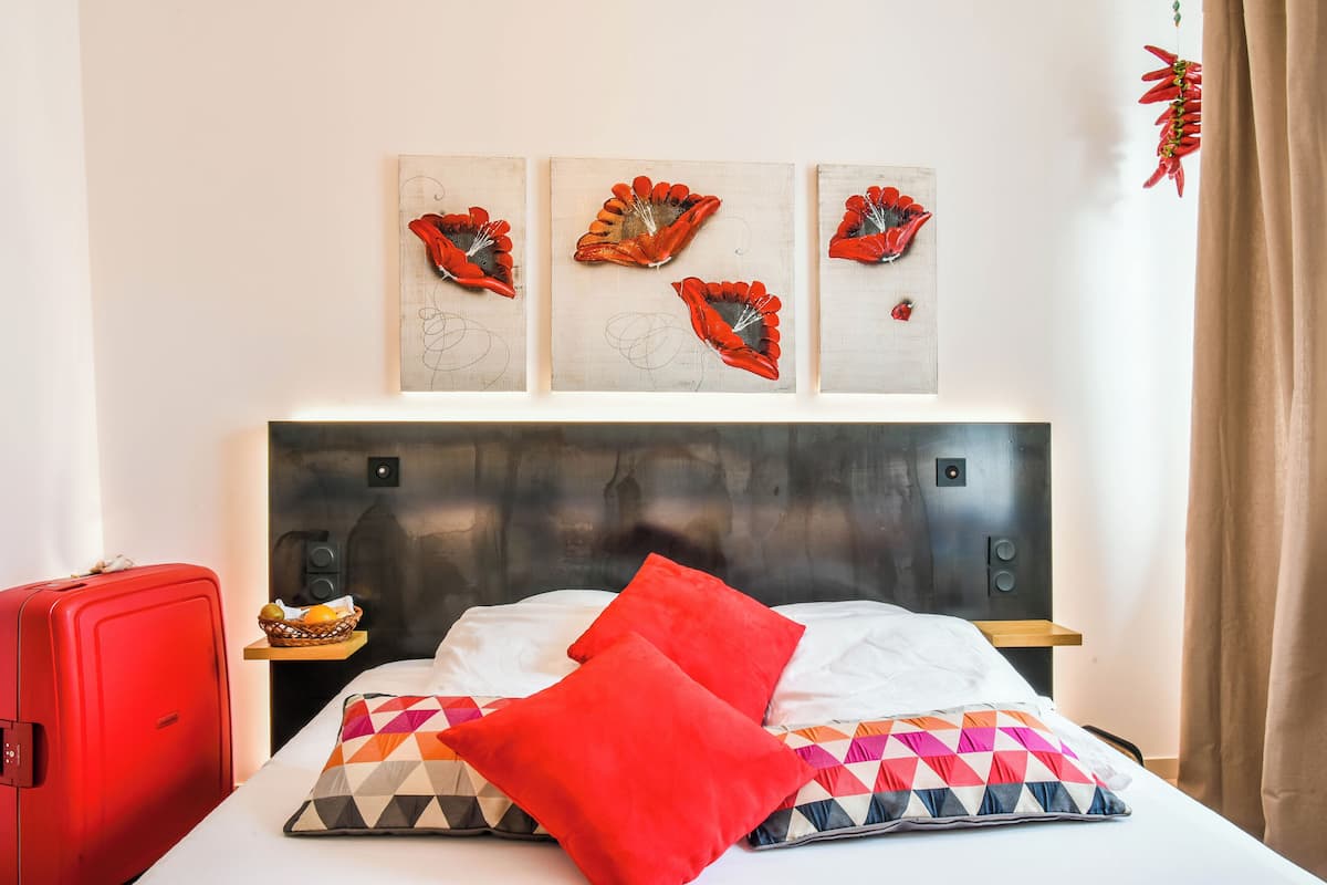 Ein Hotelzimmer mit einem Bett, einem roten Koffer und Bildern an der Wand.