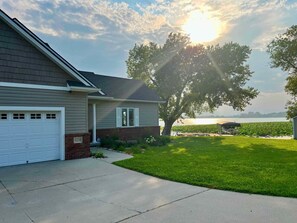 Une maison d’habitation avec un garage, une pelouse bien entretenue et un grand arbre à l’avant.