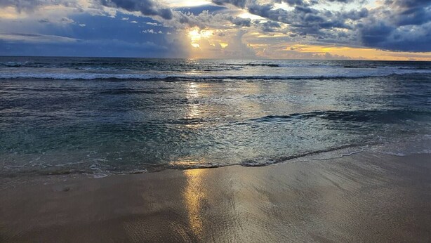 Uma praia com ondas e céu nublado.