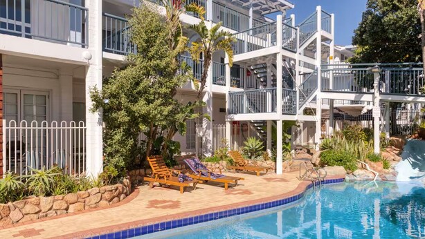 A hotel with a pool area, including lounge chairs and a water slide. - Coastal Scarborough Beach • Chic • Pool View • 2BR (Scarborough)