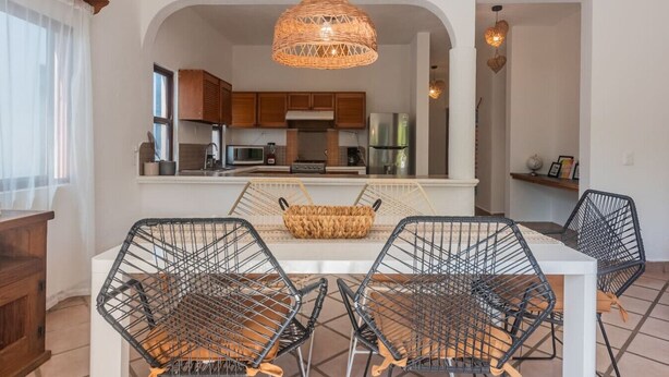 A modern kitchen with white cabinets, a stainless steel refrigerator, and a hanging woven light fixture. - Spacious 2 bdrm + A/C, 2 bdrm + A/C in Playacar (Playa del Carmen)