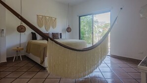 A room with a hammock, a bed, a small stool, a wall hanging, and a large window. - Spacious 2 bdrm + A/C, 2 bdrm + A/C in Playacar (Playa del Carmen)