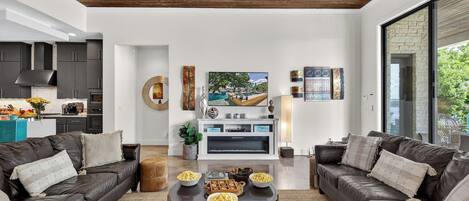 Una sala de estar moderna con sofás de cuero, una mesa de centro con cuencos, una chimenea y una cocina al fondo.