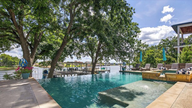 A swimming pool with a deck, lounge chairs, and a view of a body of water. - Lakeshore Landing | Concierge Services (Kingsland)