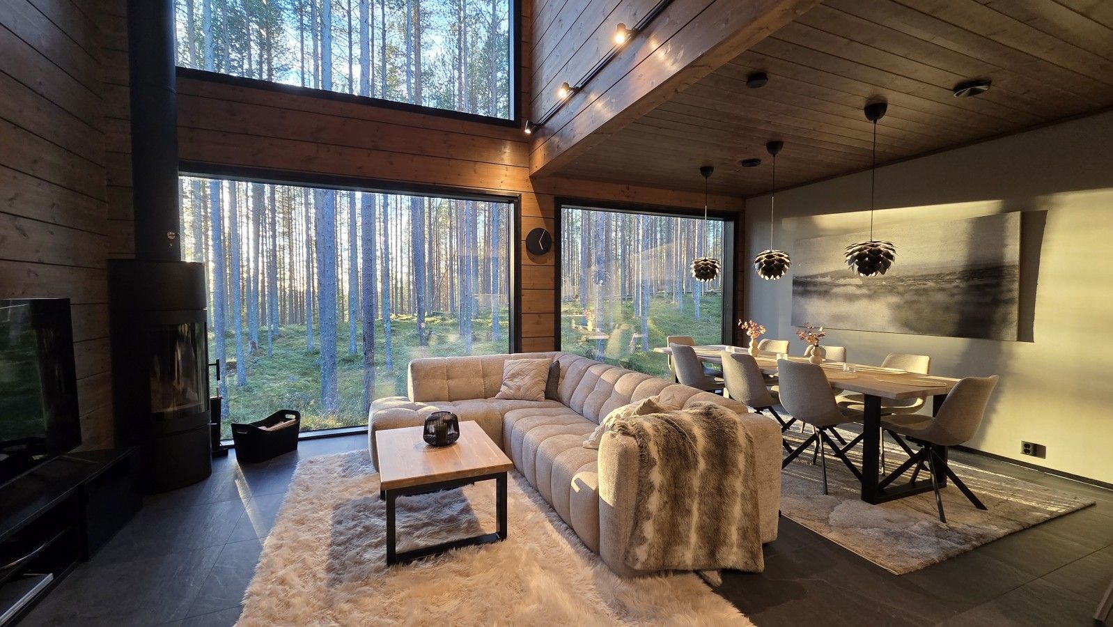 A modern living room with a large window, a sofa, a coffee table, and a dining area with chairs.