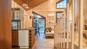 A modern log cabin interior with a kitchen, dining area, and a cozy living space.