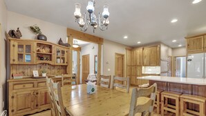A spacious kitchen with wooden cabinets, a central island, and a chandelier.