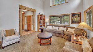 A spacious living room with a large window, a sofa, a coffee table, and a chair.