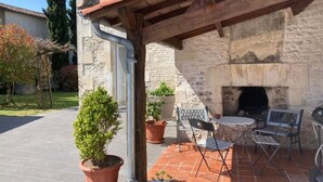 An outdoor patio with stone walls, a fireplace, and outdoor seating. - GITE DES VIGNES (Archiac)
