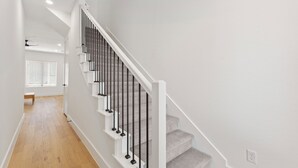 A staircase with white railings and carpeted steps leading to an upper floor.
