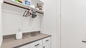A kitchen with white cabinets, a countertop, and a hanging rack with utensils.