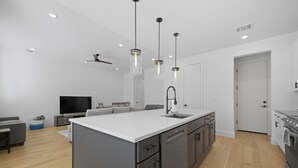 A modern kitchen with a central island, built-in appliances, and pendant lighting.