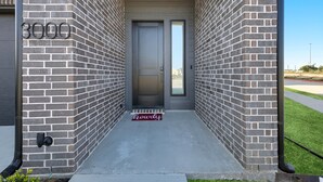 A modern building entrance with a brick facade, a door, and a number "3000" sign.