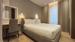 Ein modernes Hotelzimmer mit einem großen Bett, einem Schreibtisch und einem Spiegel.