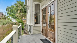 Une terrasse en bois avec une balustrade blanche, une porte à panneaux de verre et un petit espace de véranda.