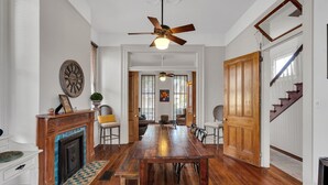 Une salle à manger spacieuse avec une table et des chaises en bois, une cheminée et un ventilateur de plafond.