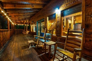 A wooden cabin with a porch, wooden chairs, and a kitchen area visible through the windows. - Free Dollywood Tix/Pool/Modern/Luxurious/Secluded (Sevierville)