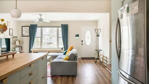 A modern kitchen with a large refrigerator, wooden cabinets, and a dining area with a table and chairs. - Porch & Yard, Spacious & Cozy, Close to Downtown! (Raleigh)