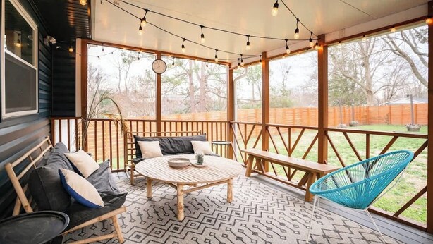 A covered patio with a wooden bench, a round table, and a blue chair. - Porch & Yard, Spacious & Cozy, Close to Downtown! (Raleigh)