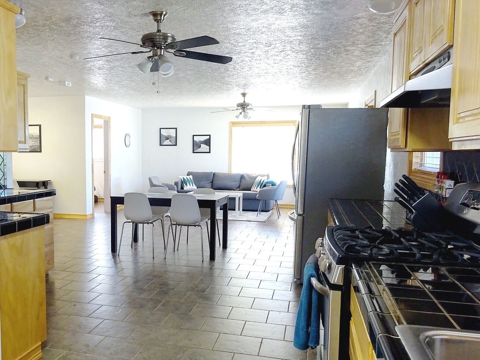 A kitchen with a stove, oven, and ceiling fan. There is a dining area with a table and chairs.